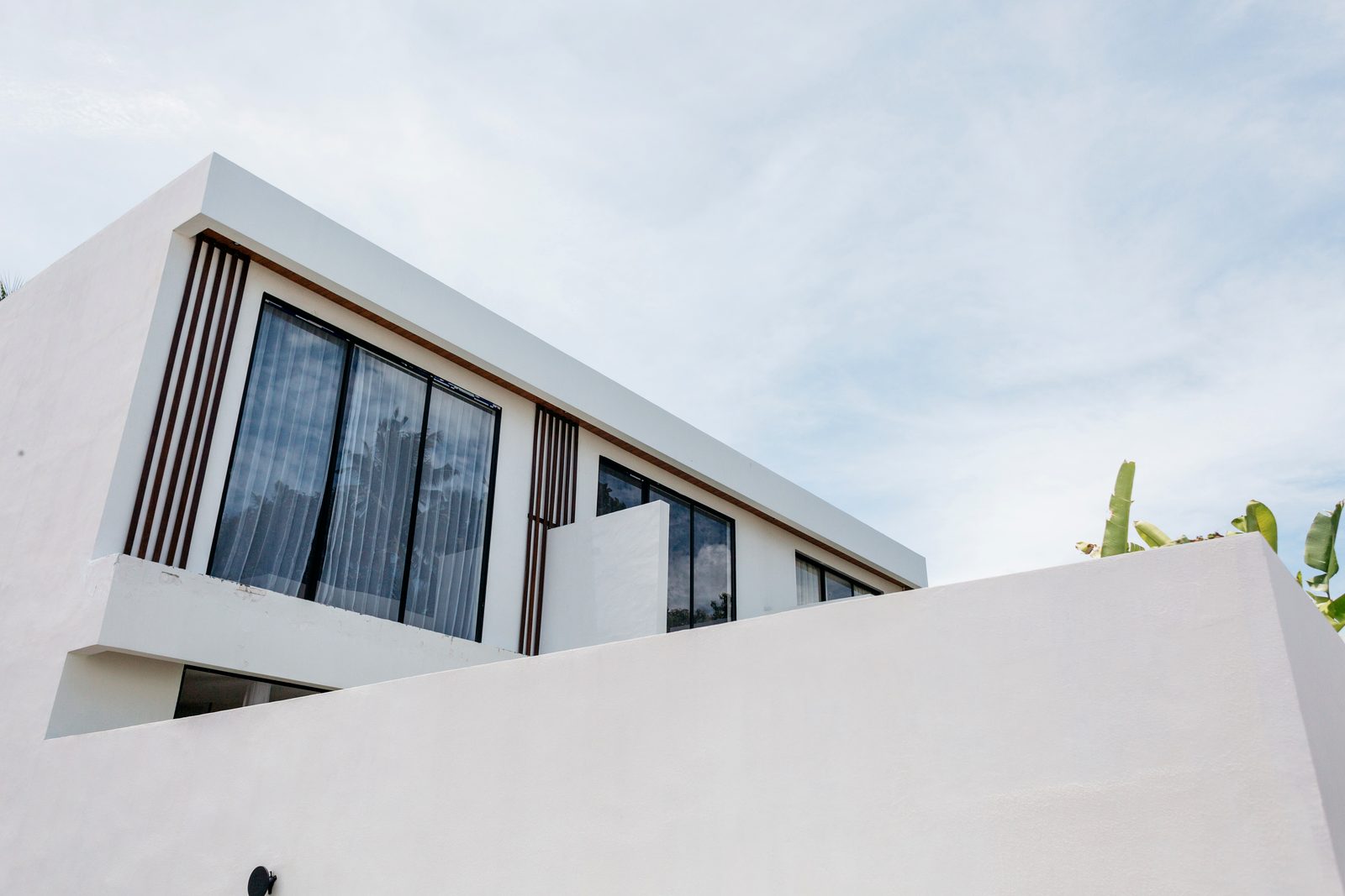 Clean modern villa lines and teak-screen façade against blue sky — Santara Villas Resort, Ubud