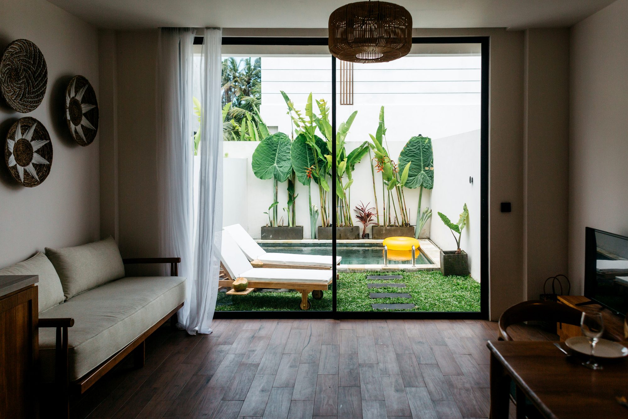 Open-plan living room opening to a private pool garden — boutique villa interior, Ubud