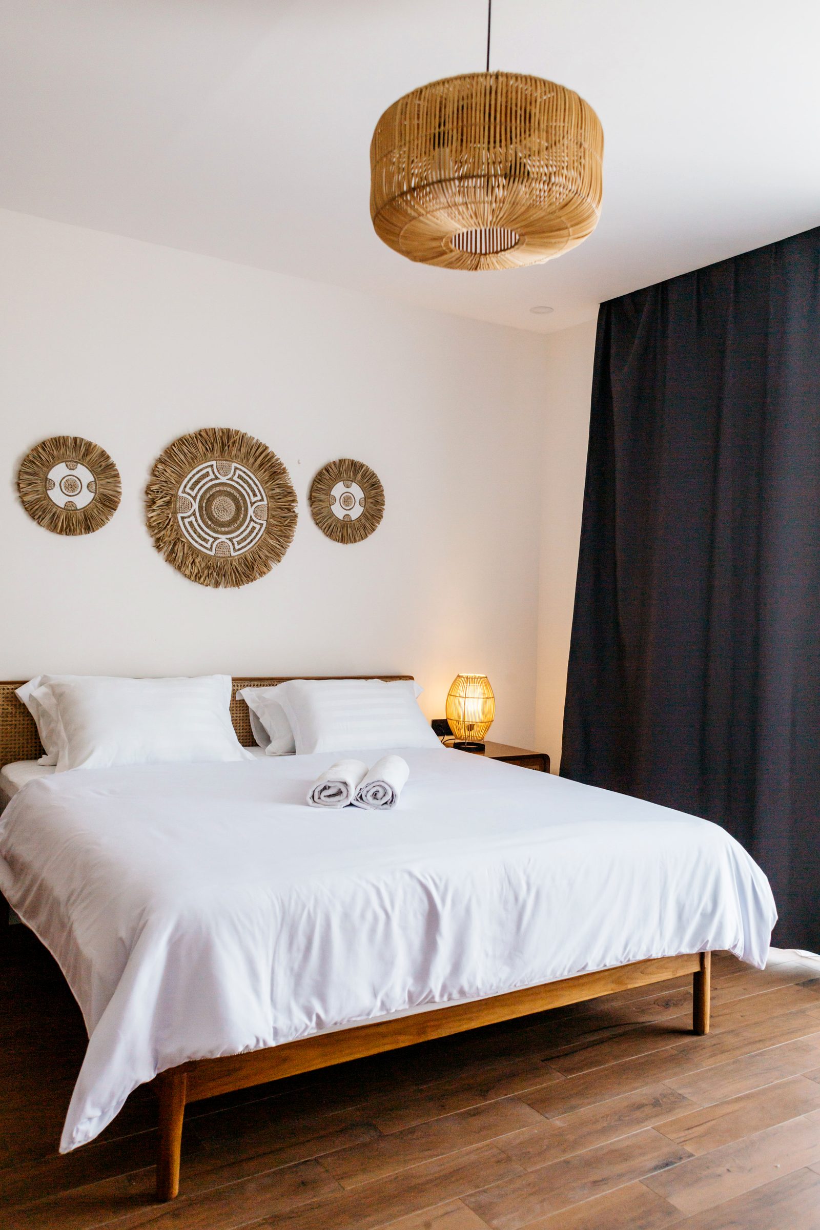 Master bedroom with teak bed, rattan pendant and woven art — Santara Villas Ubud